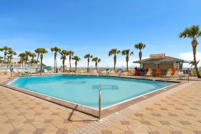a large swimming pool with palm trees and a beach at The Summit 1130 in Panama City Beach