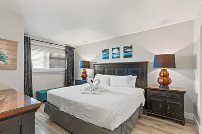 a bedroom with a bed and a desk with two lamps at The Summit 515 in Panama City Beach