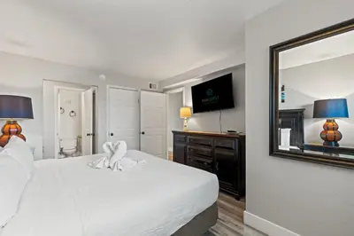 a bedroom with a white bed and a mirror at The Summit 515 in Panama City Beach