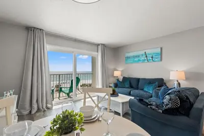 a living room with a blue couch and a view of the ocean at The Summit 515 in Panama City Beach