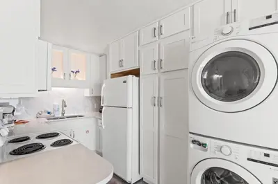 a kitchen with white cabinets and a washer and dryer at The Summit 515 in Panama City Beach