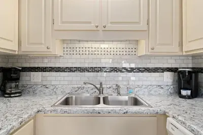 a kitchen counter with a sink and white cabinets at The Summit 1030 in Panama City Beach