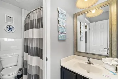 a bathroom with a sink and a toilet and a mirror at The Summit 728 in Panama City Beach