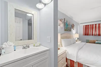a bedroom with a bed and a sink and a mirror at The Summit 502 in Panama City Beach