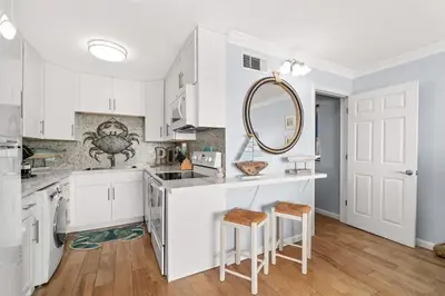 a kitchen with white cabinets and a counter with stools at The Summit 502 in Panama City Beach