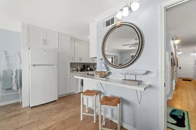 a white kitchen with a counter and a mirror at The Summit 502 in Panama City Beach