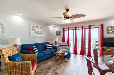 a living room with a blue couch and red curtains at The Summit 504 in Panama City Beach