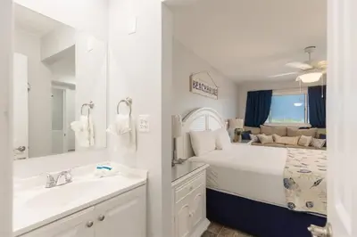 a white bedroom with a bed and a sink at The Summit 504 in Panama City Beach