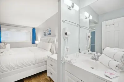 a white bedroom with a bed and a mirror at The Summit 1017 in Panama City Beach