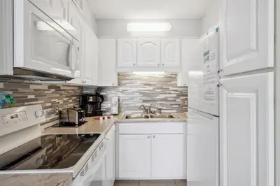 a white kitchen with white cabinets and a sink at The Summit 1017 in Panama City Beach