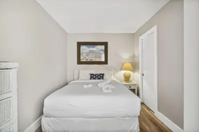 a white bedroom with a white bed and a door at Moondrifter 502 in Panama City Beach