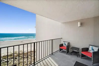 a balcony with two chairs and a view of the beach at Moondrifter 502 in Panama City Beach