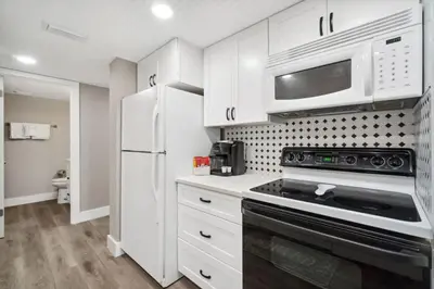a kitchen with white cabinets and a stove and microwave at Moondrifter 502 in Panama City Beach