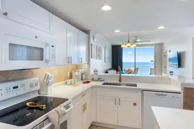 a kitchen with white cabinets and a view of the ocean at Majestic T2 - 1606 in Panama City Beach