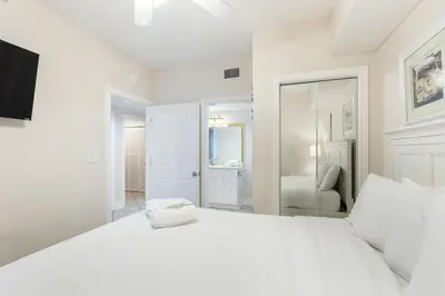 a white bedroom with a large bed and a mirror at Majestic T2 - 1606 in Panama City Beach