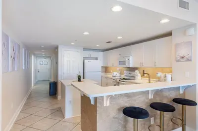 a kitchen with white cabinets and bar stools at Majestic T2 - 1606 in Panama City Beach