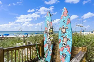 two surfboards are leaning against a fence at the beach at The Summit 531 in Panama City Beach