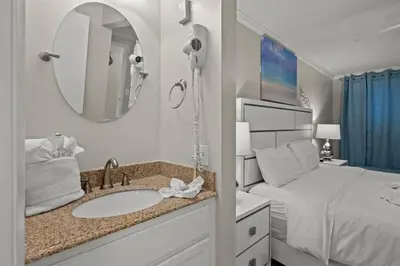 a bathroom with a sink and a bed with a mirror at The Summit 816 in Panama City Beach