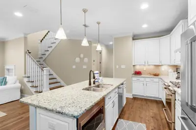 a kitchen with white cabinets and a sink and a staircase at Sunny Side Up in Santa Rosa Beach