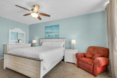 a bedroom with a bed with a ceiling fan and a chair at Majestic Beach Towers 2-1708 in Panama City Beach