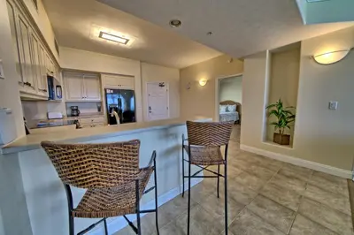 a kitchen with two bar stools and a counter at Luxurious Tropical Condo with Breathtaking Gulf View - Unit 2006 in Panama City Beach