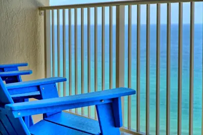 a blue bench sitting on a balcony overlooking the ocean at Wondrous Condo with Beach Access and Poolside Beach - Unit 2103 in Panama City Beach