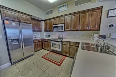 a kitchen with wooden cabinets and stainless steel appliances at Wondrous Condo with Beach Access and Poolside Beach - Unit 2103 in Panama City Beach