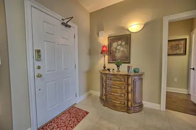a hallway with a white door and a table with a lamp at Roomy Oceanfront Condo with Breathtaking View and Beachside Pool - Unit 1906 in Panama City Beach