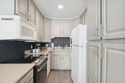 a kitchen with white cabinets and a white refrigerator at The Summit 215 in Panama City Beach