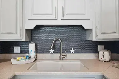 a kitchen counter with a sink and white cabinets at The Summit 215 in Panama City Beach