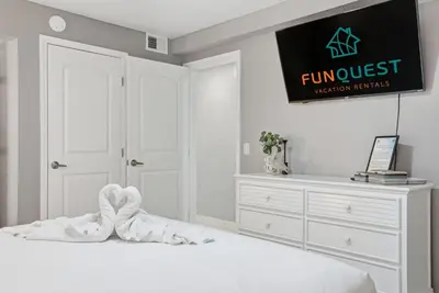a white bedroom with a white bed and a dresser at The Summit 1217 in Panama City Beach