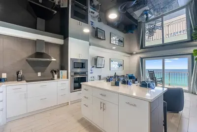 a kitchen with white cabinets and a view of the ocean at The Summit 1205 in Panama City Beach