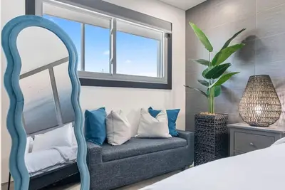 a bedroom with a blue chair and a mirror at The Summit 1205 in Panama City Beach