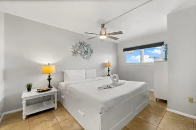 a white bedroom with a bed and a ceiling fan at The Summit 620 in Panama City Beach