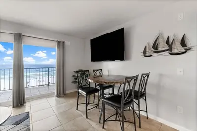 a dining room with a table and chairs and a television at The Summit 620 in Panama City Beach