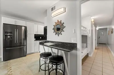 a white kitchen with a counter and stools in it at The Summit 620 in Panama City Beach