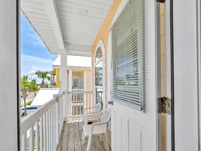 a porch with a white door and a chair at Ocean Spray in Panama City