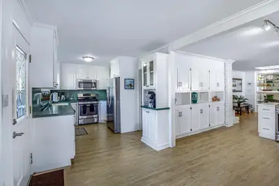 a kitchen with white cabinets and a wooden floor at Bay Shore in Panama City Beach