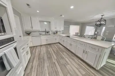 a large kitchen with white cabinets and a wooden floor at Sandy Feet Retreat in Panama City Beach