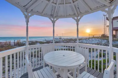 a white table and chairs on a porch with the beach at Sandy Feet Retreat in Panama City Beach