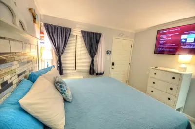 a bedroom with a blue bed with a tv on the wall at Sea Glass Villa in Panama City Beach