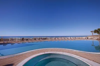 a large swimming pool with chairs and the beach at Club Wyndham Panama City Beach in Panama City Beach