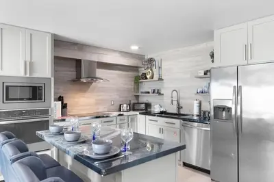 a kitchen with white cabinets and a stainless steel refrigerator at The Summit 616 in Panama City Beach