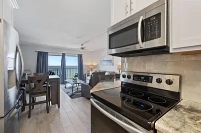 a kitchen with a stove top oven next to a living room at The Summit 621 in Panama City Beach