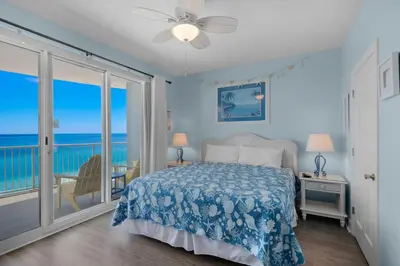 a bedroom with a bed and a balcony with the ocean at Twin Palms 1201 in Panama City Beach