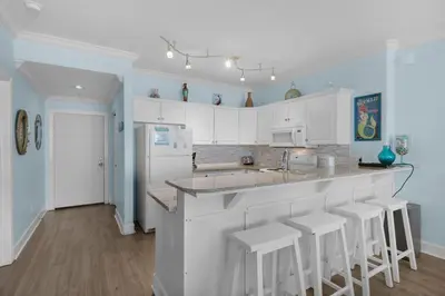 a kitchen with white cabinets and bar stools at Twin Palms 1201 in Panama City Beach