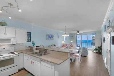 a kitchen with white cabinets and a dining room at Twin Palms 1201 in Panama City Beach