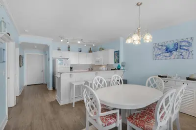 a kitchen and dining room with a white table and chairs at Twin Palms 1201 in Panama City Beach
