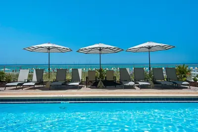 a group of chairs and umbrellas next to a swimming pool at Twin Palms 1201 in Panama City Beach