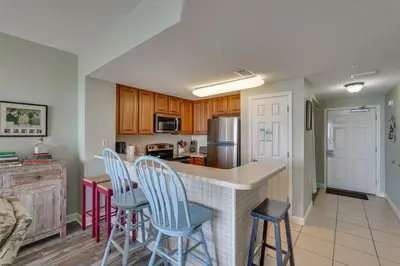 a kitchen with a bar with stools in it at Gulf Coast Getaway with Balcony and Resort Amenities! in Panama City Beach